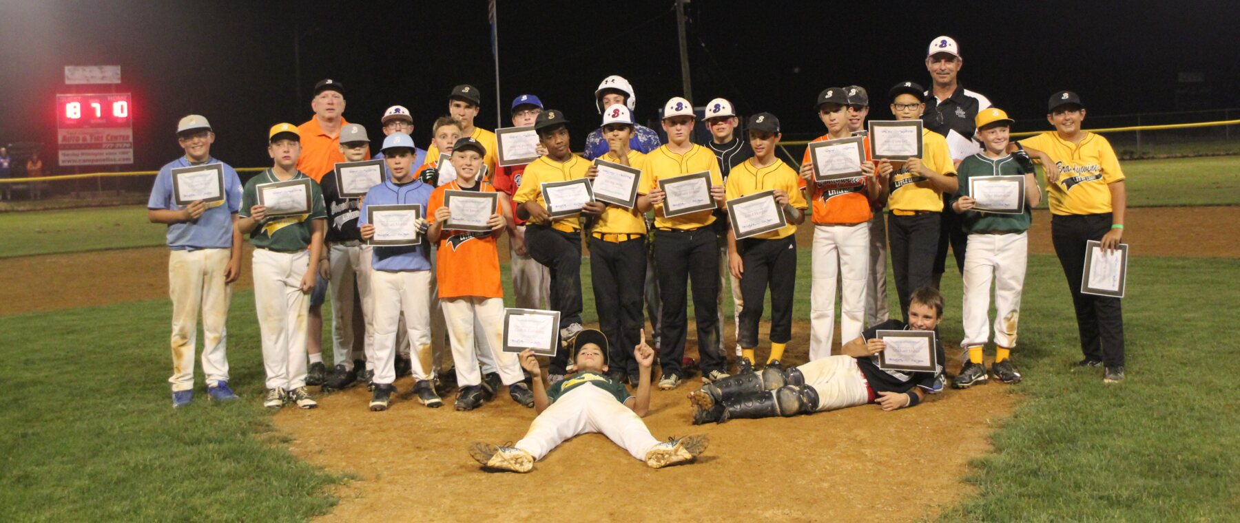 The 2017 Brandywine Little League graduates and coaches together on the field holding their certificates