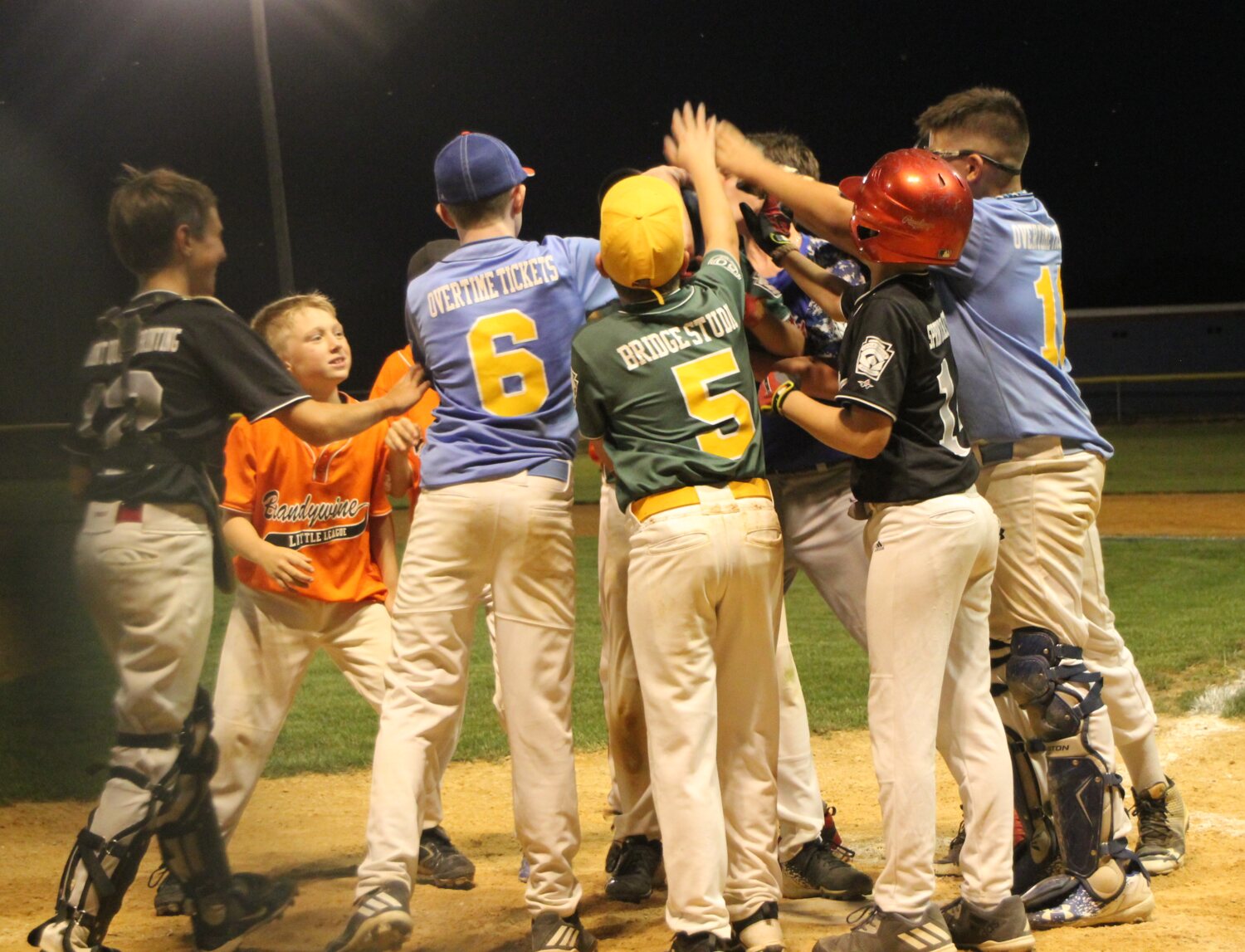 Players from the 2017 Graduation Game celebrating a home run together at home plate
